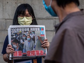 A volunteer poses holding a copy of the Apple Daily newspaper — paid for by a collection of pro-democracy district councillors — before handing them out in Hong Kong on August 11, 2020, a day after authorities conducted a search of the newspaper's headquarters after the company's founder Jimmy Lai was arrested under the new national security law.