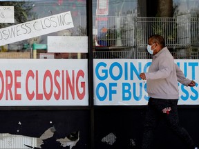 A man walks by a business that is closing due to COVID-19, in Niles, Ill., on May 21.