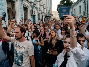 People hold up Belarusian passports as they protest outside the Belarusian embassy after polls closed in Belarus' presidential election, in Moscow on August 9, 2020.