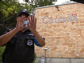 A security officer gestures outside the Canadian Embassy in Beijing, Thursday, Aug. 6, 2020. China has sentenced another Canadian citizen to death on drug charges amid heightened tension between the two countries.
