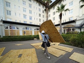 Workers board up windows at the Galvez Hotel & Spa Tuesday, Aug. 25, 2020, in Galveston, Texas, as Hurricane Laura heads toward the Gulf Coast.