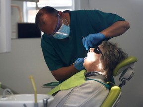 FILE PHOTO: A dentist tends to a patient at Silveroaks Dental Surgery as it opens for non aerosol generating assessments in Milton Keynes, following the outbreak of the coronavirus disease (COVID-19), Milton Keynes, Britain, June 8, 2020.