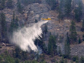 A helicopter drops water on the Christie Mountain wildfire along Skaha Lake in Penticton, B.C. Friday, Aug. 21, 2020. Wildfires in the area have forced several thousand people to be on evacuation alert.