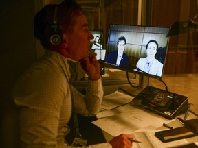 A translator works as WE Charity founders Marc Kielburger, screen left, and Craig Kielburger, screen right, appear as witnesses via videoconference during a House of Commons finance committee in the Wellington Building in Ottawa on Tuesday, July 28, 2020. The federal Conservatives are calling on WE Charity to release a series of documents that the Toronto-based youth organization promised to hand over to a House of Commons committee before Prime Minister Justin Trudeau prorogued Parliament.