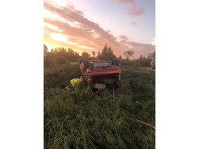 A first responder checks on an overturned vehicle at the scene where a tornado touched down, uprooting trees and overturning two vehicles near Virden, Man., in a Friday, Aug. 7, 2020, handout photo published to social media.