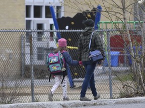 A woman walks her daughter to school in Gatineau, Que., Monday May 11, 2020. As thousands of Montreal-area students return to class, the Quebec government is facing renewed criticism from some teachers, parents and school administrators, who say the province's back-to-school directives during the COVID-19 pandemic are still unclear.