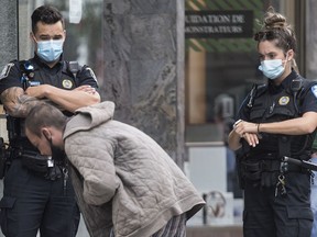 Police look on as they move a homeless man away from a street corner in Montreal, Saturday, August 22, 2020. Quebec's Public Security Department has released guidelines for the province's police forces on street checks to ensure they aren't random, unfounded or discriminatory.THE CANADIAN PRESS/Graham Hughes