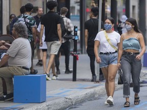 People wear face masks as they walk along a street in Montreal, Saturday, Aug. 22, 2020.