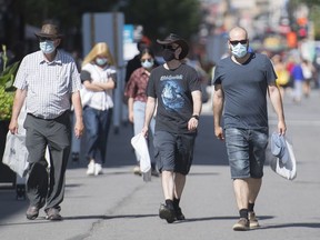 People wear face masks as they walk along Sainte Catherine Street in Montreal, Saturday, Aug. 1, 2020. While Quebec moved to allow gatherings of up to 250 people both indoors and outdoors, a Mohawk community south of Montreal isn't following suit.THE CANADIAN PRESS/Graham Hughes