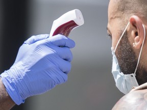 A man has temperature checked before entering a store in Montreal on July 25, 2020, as the COVID-19 pandemic continues in Canada and around the world. Community groups in Montreal say they have been forced to take matters into their own hands after the Quebec government went back on a pledge to collect race-based data to help trace the impact of COVID-19 on marginalized communities.