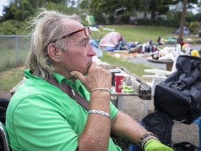 Peter Hern, 74, a resident of the Belle Island homeless encampment, is shown in Kingston, Ont., on August 18, 2020. Peter Hern rolls around the encampment where he lives in Kingston, Ont., in his wheelchair toward a large table filled with food. He grabs a bun and starts eating. About a dozen tents and a few wooden shacks dot Belle Park, the place he has called home for the past three months.