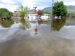 A stop sign is shown in a flooded intersection in Grand Forks, B.C., on May 17, 2018. A new report says provincial governments are not moving fast enough to protect homes and other buildings from the ravages of flooding. The report from the Intact Centre on Climate Adaptation at the University of Waterloo says on average provincial governments get a grade of C for flood preparedness.