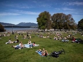 People sit and lie in the sun at Kitsilano Beach Park as temperatures reached highs into 20s according to Environment Canada, in Vancouver, on Saturday, May 9, 2020. Stronger actions to enforce public health measures are expected to be announced today in British Columbia as the number of active cases of COVID-19 rises.
