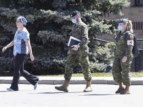 A staff member escorts members of the Canadian Armed Forces in to a long term care home, in Pickering, Ont. on Saturday, April 25, 2020. The Canadian Armed Forces says minor problems remain in some Ontario long-term care homes they were deployed to earlier in the COVID-19 pandemic.