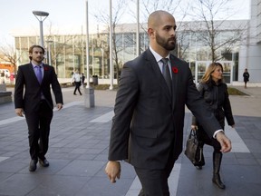 Michael Theriault, centre, and Christian Theriault, left, arrive at the Durham Region Courthouse in Oshawa, Ont., ahead of Dafonte MIller's testimony, on Wednesday, Nov. 6, 2019. Lawyers for a Toronto police officer who was found guilty of assault in the beating of a young Black man are asking the court to throw out the conviction.