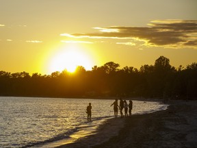 People walk along the shore at Sandbanks Provincial Park at sunset in Prince Edward, Ontario, Canada, on Saturday, June 13, 2020.