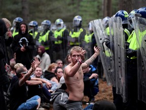 A reveller puts his hands up in front of riot police at the scene of a suspected illegal rave in Thetford Forest, in Norfolk, Britain, August 30, 2020.