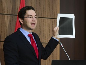 Conservative MP Pierre Poilievre holds up redacted documents during a press conference on Parliament Hill in Ottawa on Wednesday, Aug. 19, 2020. The documents were tabled by the Government at the House of Commons Finance Committee.