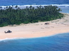 This handout photo taken on August 2, 2020 and received on August 4 from the Australian Defence Force shows an Australian Army ARH Tiger helicopter landing near the letters "SOS" (C) on a beach on Pikelot Island where three men were found in good condition after being missing for three days.