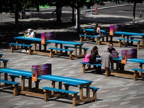 People sit at picnic tables on the plaza outside the Vancouver Art Gallery, in Vancouver, B.C., Monday, Aug. 3, 2020.