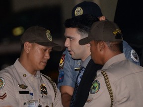In this file photo taken on December 1, 2015, U.S. Marine Lance Corporal Joseph Scott Pemberton (C) is escorted by Philippine policemen shortly after arriving at Camp Aguinaldo in Quezon City, from Olongapor city where a court convicted him of homicide for the killing of Jennifer Laude in a motel in October 2014.