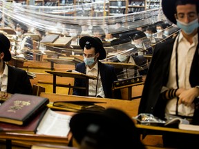 Ultra-Orthodox Jewish men pray behind a plastic screen during morning prayers in a Jewish seminary in Bnei Brak, Israel, on Sept. 9.