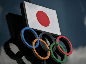 The Olympic Rings and the Japanese flag outside the Olympic Museum in Tokyo, August 24, 2020. Tokyo's postponed Olympics will go ahead next year regardless of the COVID-19 coronavirus pandemic, IOC vice president John Coates told AFP on September 7, 2020, saying they would be the "Games that conquered COVID".