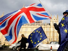 In this file photo taken on March 28, 2018 An anti-Brexit demonstrator waves a Union flag alongside a European Union flag outside the Houses of Parliament in London.