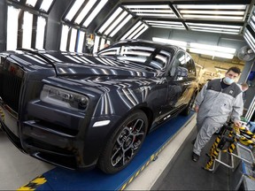 A technician walks past a Rolls-Royce car following an inspection of its' paintwork on the production line of the Rolls-Royce Goodwood factory, near Chichester, Britain, September 1, 2020.