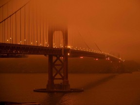 Cars drive during midday along the Golden Gate Bridge in San Francisco under an orange smoke-filled sky on September 9, 2020.  More than 300,000 acres are burning across the northwestern state including 35 major wildfires, with at least five towns "substantially destroyed" and mass evacuations taking place.