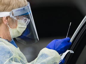 A health-care worker does a test at a drive-thru COVID-19 assessment centre at the Etobicoke General Hospital in Toronto on Tuesday, April 21, 2020.