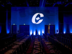 A man is silhouetted walking past a Conservative Party of Canada logo before the opening of a party convention in Halifax on Aug. 23, 2018.