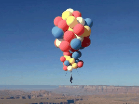 Extreme performer David Blaine hangs with a parachute under a cluster of balloons during a stunt to fly thousands of feet into the air in a still image from video taken over Page, Arizona, September 2, 2020.