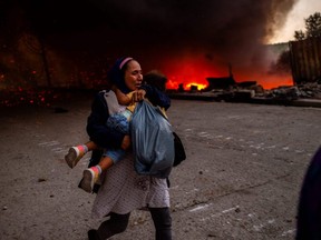 A woman and a child flee a fire burning in the Moria migrant camp, where they were living, on the Greek island of Lesbos on September 9, 2020.  More than 12,000 people seeking asylum had lived in containers and tents in the camp before the fire destroyed most of it, just hours after the migration ministry said that 35 people had tested positive for COVID-19 there.