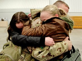 In a file photo from March 18, 2014, Lt.-Col. Lee Hammond is hugged by his daughters at the Edmonton Garrison after returning home from Afghanistan with other members of Task Force 2-13.