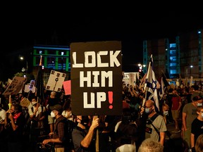 An Israeli protester lifts a placard during an anti-government demonstration in front of Prime Minister Benjamin Netanyahu's residence in Jerusalem on Sept. 20, 2020.