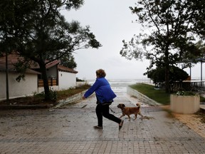 A woman walks her dog near the sea in the village of Gastouni, as a rare storm, known as a Medicane, hit western Greece, September 18, 2020.
