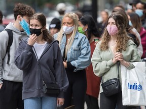 People wear face masks as they wait to enter a store in Montreal on Sept. 19, 2020.