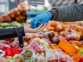 A vendor passes change to a customer purchasing fruit and vegetables from an outdoor market stall at Chrisp Street Market in Poplar, London, U.K., on Thursday, Aug. 27, 2020.