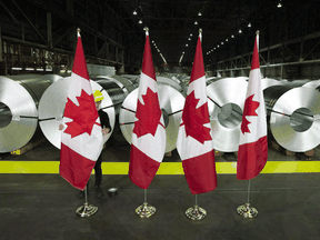 Canadian flags stand in front of rolls of coated steel at Stelco in Hamilton