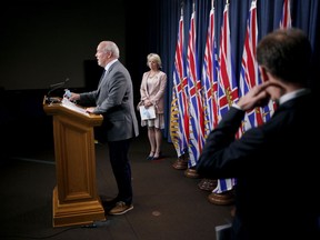 Premier John Horgan speaks as provincial health officer Dr. Bonnie Henry, centre, and health minister Adrian Dix look on during a press conference to update on the province's fall pandemic preparedness plan during a press conference from the press theatre at Legislature in Victoria, Wednesday, Sept. 9, 2020.