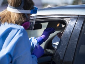 Paramedic Jessica Aiken administers a nasal swab at a drive through, pop-up COVID-19 test centre outside the Canadian Tire Centre, home of the NHL's Ottawa Senators, in Ottawa, Sunday, Sept. 20, 2020. An Ontario county is aiming to reduce the amount of time kids with mild COVID-19 symptoms are out of school by establishing testing sites exclusively for schoolchildren.