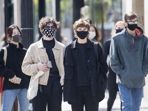People wear face masks as they wait to cross a street in Montreal, Monday, September 21, 2020, as the COVID-19 pandemic continues in Canada and around the world.