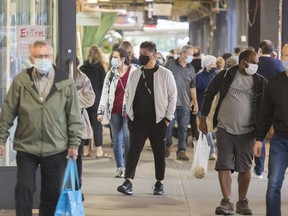 People wear face masks as they walk through a market in Montreal, Sunday, Sept. 13, 2020, as the COVID-19 pandemic continues in Canada and around the world. The Quebec government has introduced fines for individuals caught not wearing face masks or coverings in indoor public spaces.