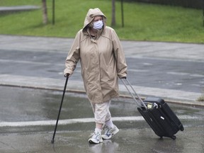 A woman wears a face mask as she crosses a street in Montreal, Saturday, Aug. 29, 2020, as the COVID-19 pandemic continues in Canada and around the world.