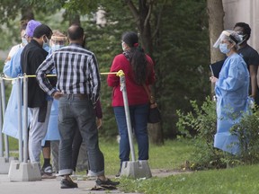 A health-care worker talks with people outside a COVID-19 testing clinic in Montreal, Monday, September 7, 2020, as the COVID-19 pandemic continues in Canada and around the world.