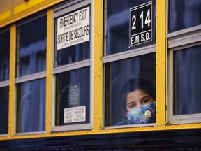 A student peers through the window of a school bus as he arrives at the Bancroft Elementary School in Montreal, on August 31, 2020. School bus cancellations are piling up in Ontario as transportation providers cite COVID-19 fears that have worsened a shortage of bus drivers in the industry. Twelve bus routes were cancelled in both the Grey-Bruce and Thunder Bay regions as of Wednesday, with providers saying health concerns from the pandemic are keeping drivers off the job.