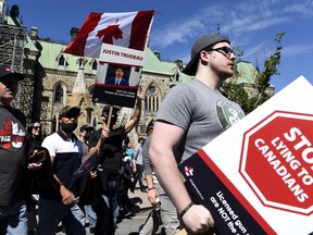 Gun owners hold signs criticizing Prime Minister Justin Trudeau as they participate in a rally organized by the Canadian Coalition for Firearm Rights against the government's new gun regulations, on Parliament Hill in Ottawa, on Saturday, Sept. 12, 2020.