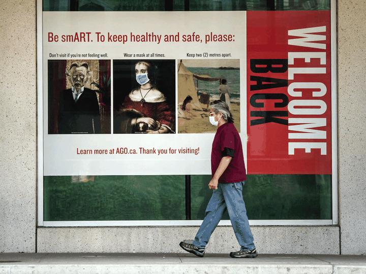  A pedestrian in Toronto walks past an Art Gallery of Ontario poster promoting COVID-19 awareness.