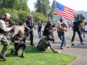 Police officers try to break up a fight between supporters of U.S. President Donald Trump and Black Lives Matter protesters outside the Oregon State Capitol building in Salem, Oregon, U.S. September 7, 2020.